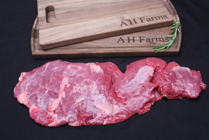 a raw skirt steak next to AH Farm's cutting boards